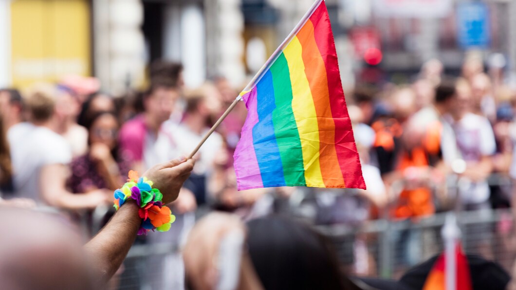 Regenboogvlag tegen een achtergrond van een grote groep demonstrerende mensen