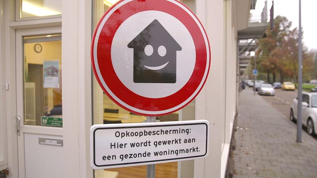 Verbodsbord met een glimlachend huis en de tekst "Opkoopbescherming: hier wordt gewerkt aan een gezonde woningmarkt"