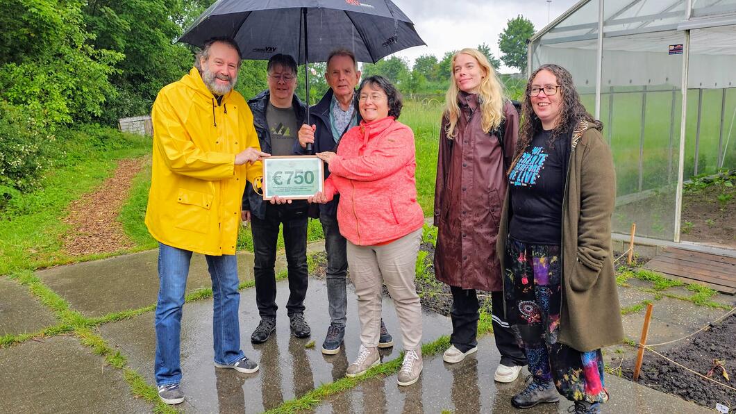 Fractievoorzitter Yorick Haan overhandigt een cheque van €750 aan coördinator Sylvia Olthuis van Voedselbanktuinieren Schiedam