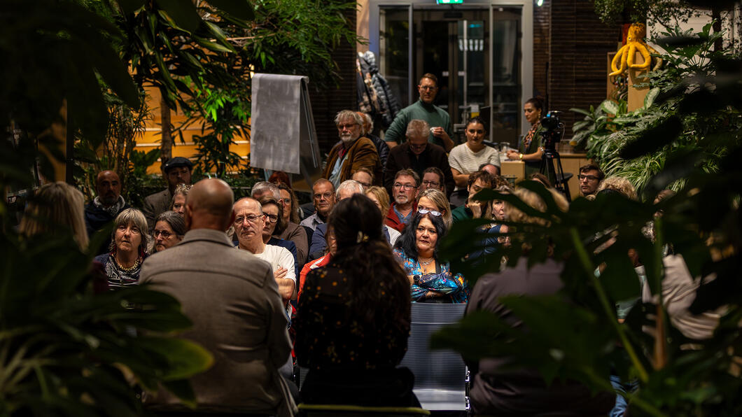 Een volle Korenbeurs kijkt en luistert naar het panelgesprek over femicide