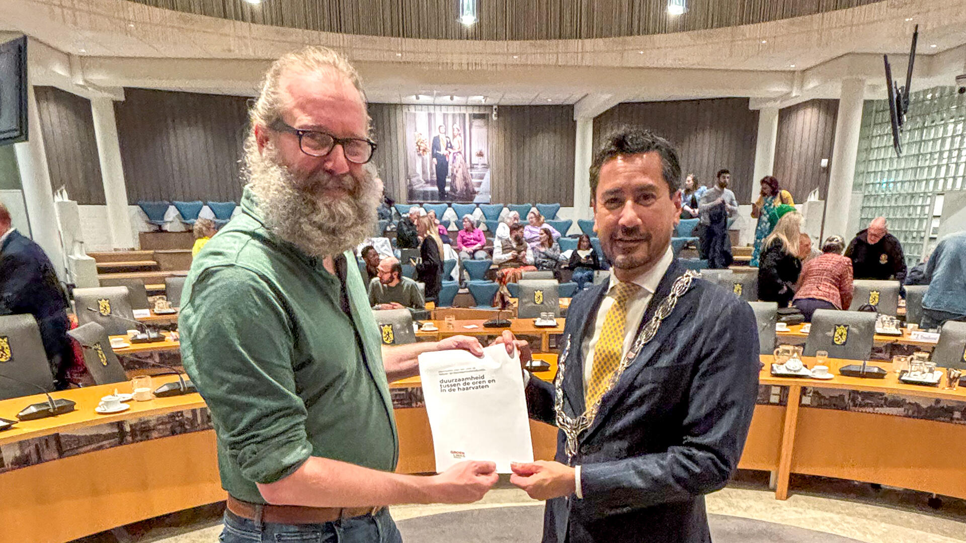 GroenLinks-fractievoorzitter Yorick Haan overhandigt zijn startnotitie "Duurzaamheid tussen de oren en in de haarvaten" aan burgemeester Harald Bergmann.